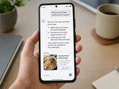 Una mano che regge uno smartphone su cui è visualizzata una risposta generata dall’intelligenza artificiale, con un annuncio sponsorizzato sotto di essa