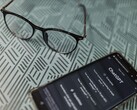 Smartphone con l’app ChatGPT aperta accanto a un paio di occhiali su una superficie a motivi