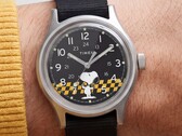 Primo piano del quadrante nero del Timex MK1 che raffigura Snoopy su uno sfondo a scacchi gialli e neri con indici arabi e lancette luminescenti.