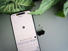 Smartphone con l’app ChatGPT aperta, appoggiato su un laptop accanto alle foglie di una pianta