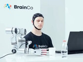 Un utente della tecnologia di controllo mentale di BrainCo che afferra meccanicamente una mela con il solo potere del pensiero.