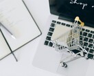 Carrello della spesa in miniatura sulla tastiera di un laptop, con la scritta «Acquista ora» sullo schermo