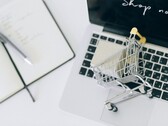 Carrello della spesa in miniatura sulla tastiera di un laptop, con la scritta «Acquista ora» sullo schermo