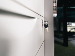 Una chiave inserita nella serratura di un cassetto di legno chiuso