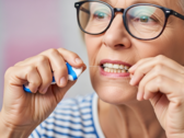 Un'immagine di una donna che passa il filo interdentale. Il filo interdentale potrebbe diventare un nuovo mezzo di vaccinazione (Fonte: Immagine generata dall'AI)