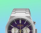 Primo piano della metà superiore del Seiko HGK003, che mette in risalto la cassa angolare in acciaio inossidabile, le maglie superiori del bracciale, i pulsanti superiori e la parte superiore del quadrante viola su uno sfondo con una vivace sfumatura di verde e blu.