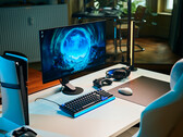 Una configurazione da gaming essenziale in studio, caratterizzata dal monitor Sony Inzone M10S II posizionato su una scrivania bianca, affiancato da una console PlayStation 5 Pro in posizione verticale, una tastiera meccanica, un mouse wireless e cuffie con una delicata illuminazione blu.