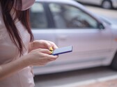 Una donna che digita sul suo smartphone con un'auto argentata sullo sfondo
