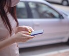 Una donna che digita sul suo smartphone con un'auto argentata sullo sfondo
