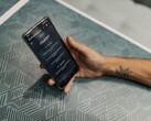 Mano che tiene uno smartphone con l'app ChatGPT aperta sopra un tavolo decorato con un motivo