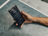 Mano che tiene uno smartphone con l'app ChatGPT aperta sopra un tavolo decorato con un motivo