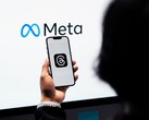 Una mano tiene uno smartphone davanti a un grande logo Meta