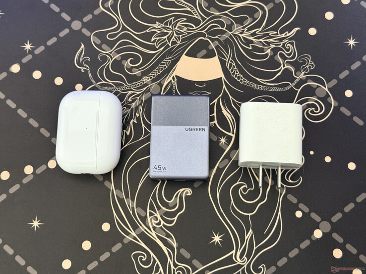 L'Ugreen Nexode Air 45W Slim accanto alla custodia degli AirPods Pro e a un caricabatteri Apple e da 18W