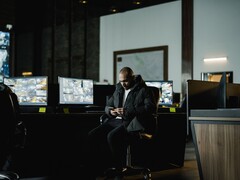 Un analista della sicurezza in una sala di controllo, davanti a diversi monitor