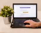 Un computer portatile su una scrivania con la posta in arrivo aperta, accanto a una pianta in vaso.