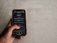 Mano che tiene uno smartphone con l'interfaccia di ChatGPT visualizzata sullo schermo sopra una superficie in pietra grigia