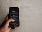 Mano che tiene uno smartphone con l'interfaccia di ChatGPT visualizzata sullo schermo sopra una superficie in pietra grigia
