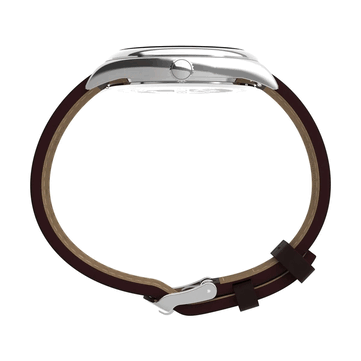 Profilo laterale del Timex Legacy Day and Date, che mette in risalto la cassa in acciaio inossidabile lucidato, la corona zigrinata, le anse curve e il cinturino in pelle marrone su uno sfondo bianco.