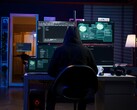 Un ricercatore incappucciato lavora su più schermi in un ambiente buio. Nella foto un hacker generico. 