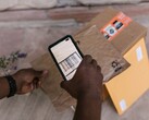 Una mano tiene uno smartphone sopra un pacco e ne scansiona il codice a barre.