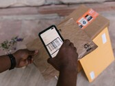 Una mano tiene uno smartphone sopra un pacco e ne scansiona il codice a barre.