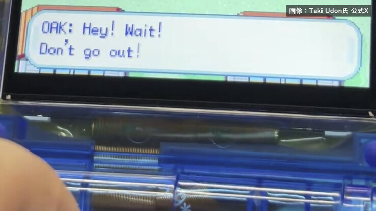 Primo piano della console portatile FPGBA SP blu trasparente, che mostra la cerniera pieghevole e un dialogo di Pokémon sullo schermo.