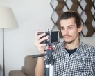 Un giovane si riprende a casa con uno smartphone montato su un treppiede