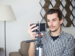 Un giovane si riprende a casa con uno smartphone montato su un treppiede