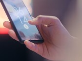 Una mano tiene in mano uno smartphone e lo sblocca utilizzando il sensore di impronte digitali sulla schermata di blocco.