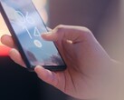 Una mano tiene in mano uno smartphone e lo sblocca utilizzando il sensore di impronte digitali sulla schermata di blocco.