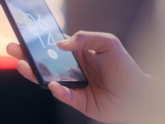 Una mano tiene in mano uno smartphone e lo sblocca utilizzando il sensore di impronte digitali sulla schermata di blocco.