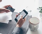 Persona che digita su uno smartphone mentre tiene una carta di credito nell’altra mano