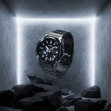 G-Shock GST-B1000BD-1A sospeso sopra rocce scure in uno spazio espositivo in cemento, mettendo in evidenza la sua costruzione in acciaio inossidabile nero.