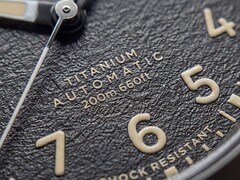 Primo piano del quadrante nero testurizzato del Timex Expedition Field Post Titanium con numeri arabi, lancette e indici luminescenti e datario.