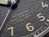 Primo piano del quadrante nero testurizzato del Timex Expedition Field Post Titanium con numeri arabi, lancette e indici luminescenti e datario.