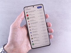 Una mano regge uno smartphone sul cui schermo è visualizzato un elenco di aggiornamenti.