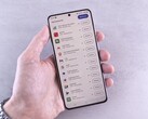 Una mano regge uno smartphone sul cui schermo è visualizzato un elenco di aggiornamenti.