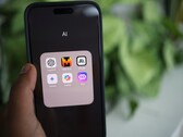 Mano che tiene uno smartphone con una cartella piena di app di IA sullo schermo