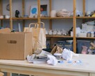 Scatola di cartone e sacchetti di carta su un tavolo di legno in un ufficio con scaffali