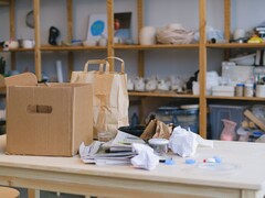 Scatola di cartone e sacchetti di carta su un tavolo di legno in un ufficio con scaffali