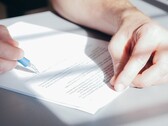 Una mano firma un documento con una penna a sfera blu