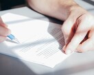 Una mano firma un documento con una penna a sfera blu