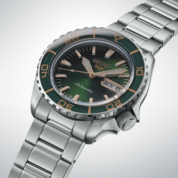 Primo piano del Seiko 5 Sports SKX HDB005, che mette in risalto il quadrante verde scuro, le lancette e gli indici applicati color oro rosa e la lunetta verde abbinata con marcature color oro.