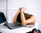 Donna che guarda il proprio smartphone con un computer portatile accanto a sé