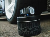 Orologio Casio G-Shock DW5600TT25-1 x Toyo Tires esposto su una scatola di metallo a tema pneumatici, accanto a una ruota di automobile.