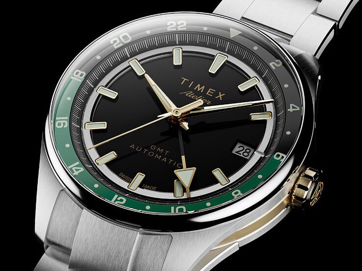 Vista angolata del Timex Atelier GMT Première M1a, che mostra il quadrante nero, l’anello GMT verde, la corona color oro e il bracciale in acciaio inossidabile.