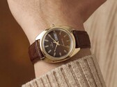 Timex Q 1978 Day and Date con quadrante fumé marrone e cassa color oro, mostrato al polso con un cinturino in pelle marrone.