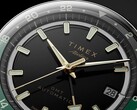 Close-up of the Timex Atelier GMT Première M1a’s black dial with gold-tone hands, luminous hour markers, date window, and black-and-green 24-hour GMT ring.