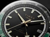 Close-up of the Timex Atelier GMT Première M1a’s black dial with gold-tone hands, luminous hour markers, date window, and black-and-green 24-hour GMT ring.