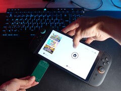 Yu del canale YouTube Better Gaming tiene in una mano un Nintendo Switch 2 e nell'altra un adattatore PCB verde open-source, cercando di inserirlo nello slot microSD Express del dispositivo (Fonte immagine: Better Gaming via YouTube)